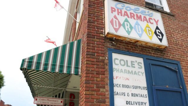 A sign on a building reading Cole's Pharmacy Drugs
