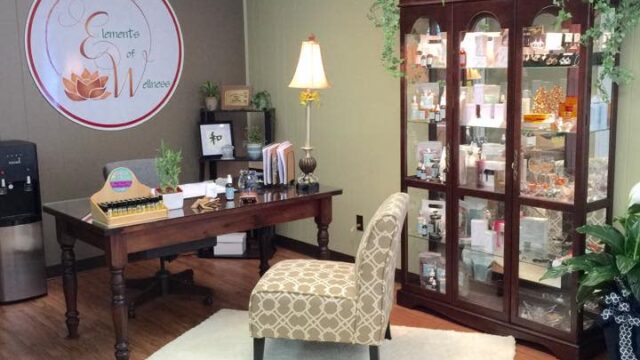 A desk with an upholstered armchair in front and a china cabinet filled with items on one side