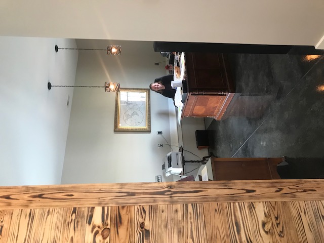 A person smiles and sits at a wooden desk in a law office