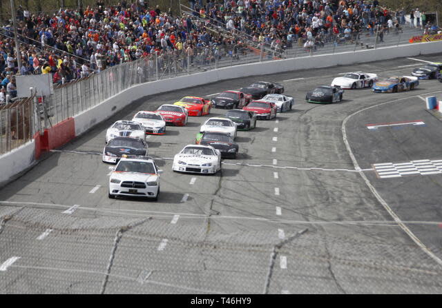 A group of motor cars cross the finish line on the racetrack