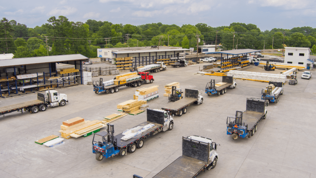 Empty flatbed trucks parked in lines, waiting to be loaded with building materials