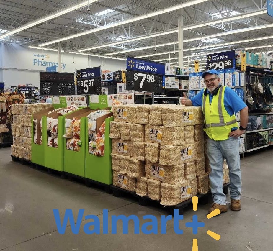 A Wal-Mart employee standing by bales of hay inside the store