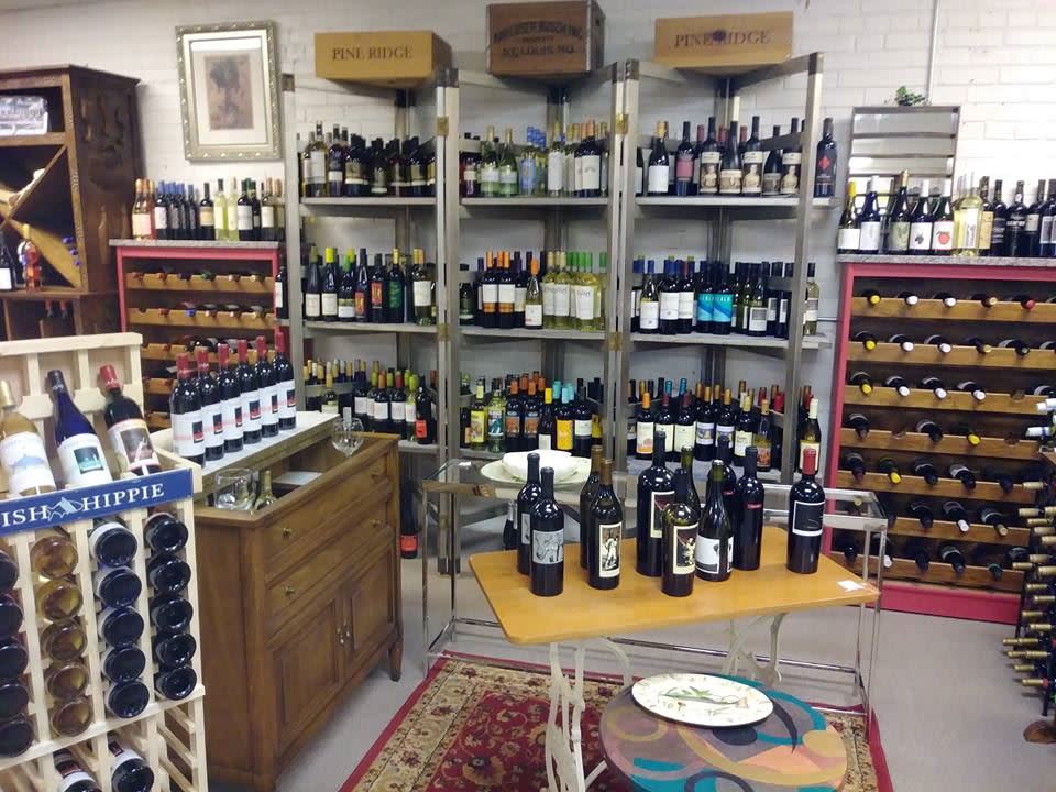 A wine shop with displays of wine along the wall and a small table with bottles of wine for sampling