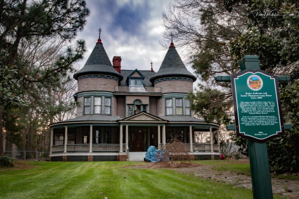 A historic two-story house with two towers and a front porch