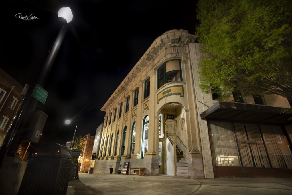 A nighttime street view of a white two-story building